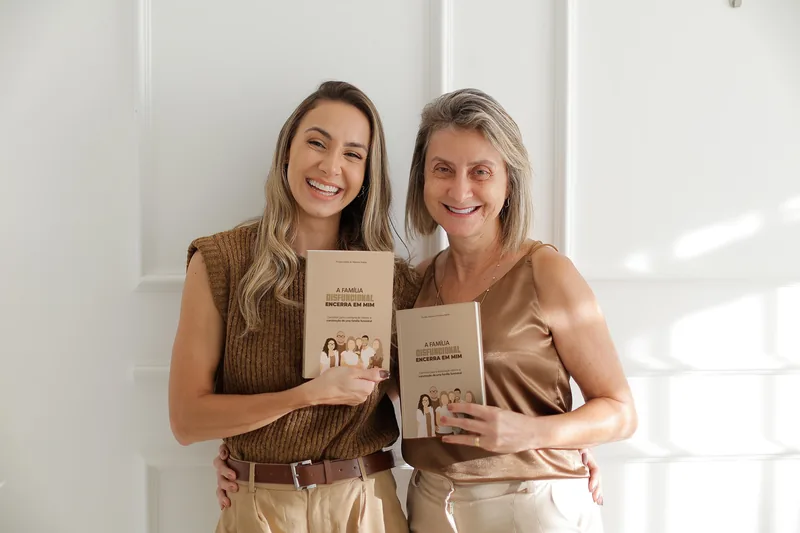 Mariana e Viviane Adelar lado a lado, cada uma segurando um exemplar do livro